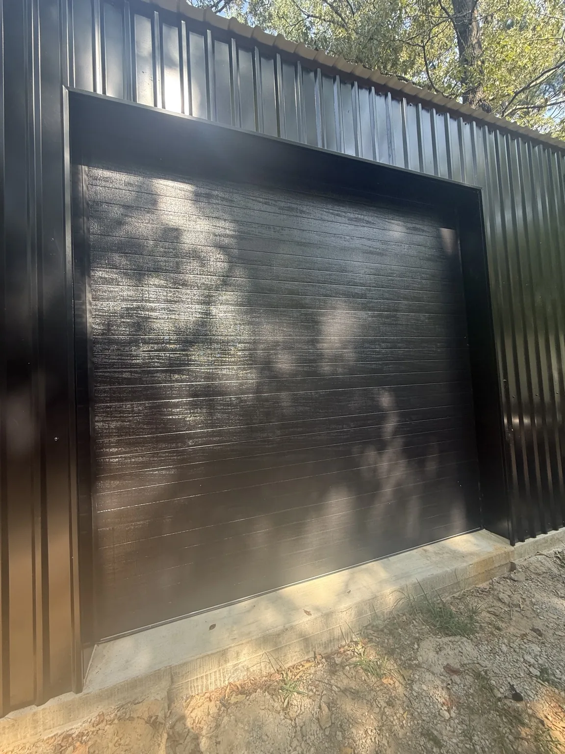 Black insulated overhead door installed in a black metal building